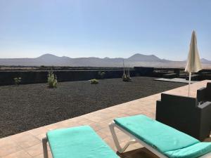 特吉塞Eslanzarote Eco Country House, Star View Area, Super wifi, Barbecue的庭院配有两把椅子和一把遮阳伞