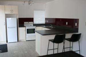 OkoroireBridgehaven Guesthouse的厨房配有白色橱柜和黑色台面