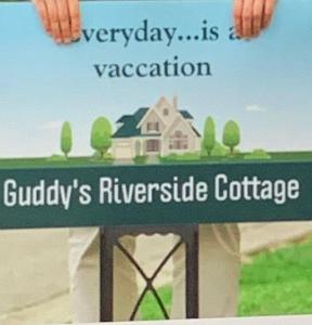 NausoriGuddy’s Riverside Cottage的门顶上有一个房子的绿色标志