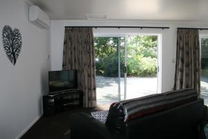 OkoroireBridgehaven Guesthouse的带沙发和滑动玻璃门的客厅