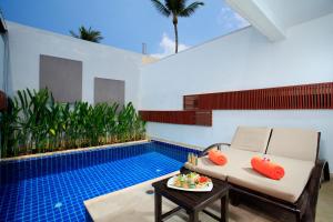 芭东海滩La Flora Resort Patong - SHA Extra Plus的客厅设有游泳池、沙发和桌子