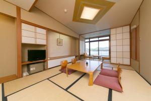 胜浦市浦岛酒店的客厅配有桌椅和电视。