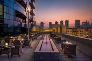 迪拜Millennium Place Barsha Heights Hotel的大楼内带桌椅的屋顶露台