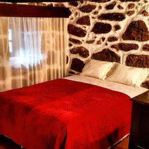 贝尔蒙特Dona Gracia Belmonte的一间卧室配有一张红色的床和石墙