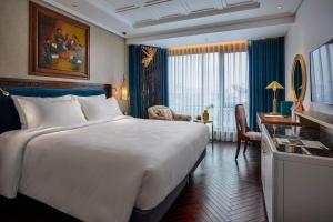 河内Peridot Grand Luxury Boutique Hotel的酒店客房设有一张大床和一张书桌。