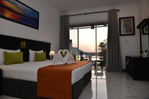 波隆纳鲁沃Agbo Hotel的一间卧室设有一张床,享有阳台的景色