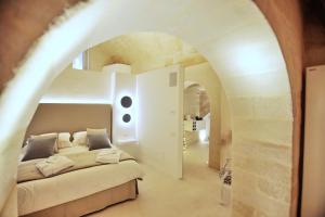 马泰拉Anima Pietra Luxury Suite的拱门上的卧室配有一张大床