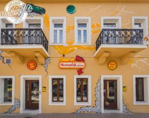 波德戈里察Hotel Marienplatz Podgorica的黄色的建筑,上面有一大堆标志