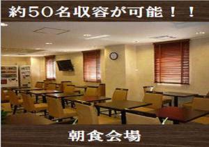 烧津市焼津駅前吴竹酒店的餐厅设有桌椅和墙上的时钟