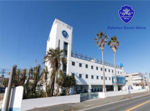 横须贺市Mykonos Resort Miura / Vacation STAY 62208的一座白色的建筑,拥有棕榈树钟楼