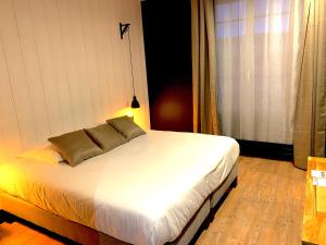 伯泽维尔Hôtel-Spa-Piscine Le Petit Castel Beuzeville-Honfleur的卧室配有白色的床和两个枕头