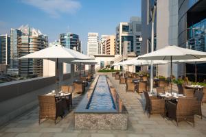 迪拜Millennium Place Barsha Heights Hotel Apartments的屋顶餐厅设有桌子和遮阳伞
