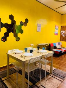 瓜拉丁加奴Ammar Homestay的黄色墙壁的房间里一张桌子和椅子