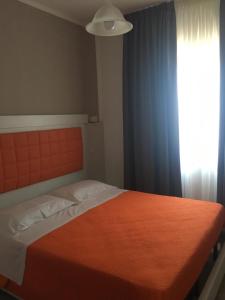 圣欧费米亚拉默齐亚Piccolo Hotel Lamezia的一间卧室配有一张带橙色毯子和窗户的床。