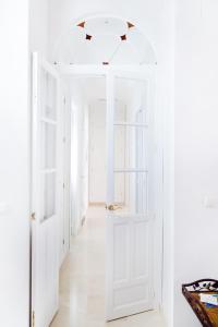 塞维利亚Hispalis Casa Palacio Apartment的一条带白色墙壁和开放式门的走廊