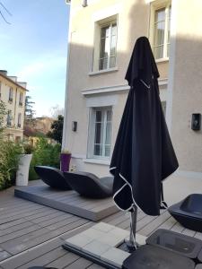 里昂chambre d'hôte Croix-Rousse的一把黑色遮阳伞,坐在一座建筑前的庭院里