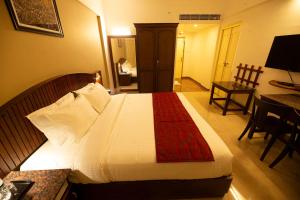 古鲁瓦尤尔Hotel Guruvayur Darshan的一间卧室配有一张带红色毯子的大床