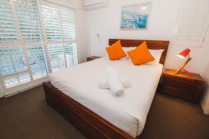 黄金海岸湖泊保护区公寓的卧室配有带橙色枕头的大型白色床