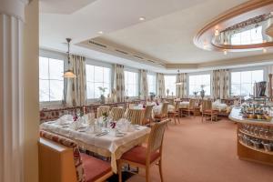 奥伯古格尔奥林匹亚酒店的餐厅设有白色的桌椅和窗户。