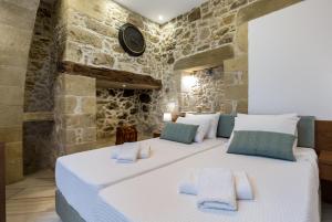 基萨莫斯Agarathos Deluxe Homes的卧室配有一张白色大床,位于石墙内