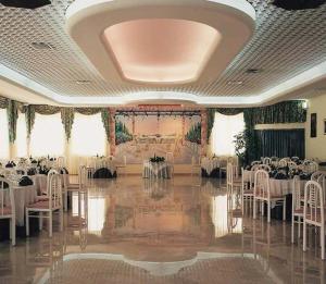 阿尔贝罗贝洛库尔迪普利亚酒店的宴会厅配有白色的桌子和白色的椅子