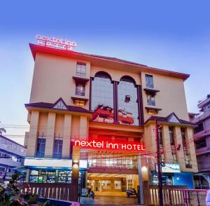 科泽科德Nextel Inn, Calicut的前面有一个红色标志的酒店
