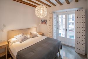 加的斯Apartamentos Son de Cadiz的一间卧室配有一张大床和一个吊灯。