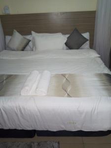 蒙巴萨BLUE NILE 9 - SUNSET HOLIDAY APARTMENTS, SHANZU - Mombasa的一张白色大床,上面有两张折叠毛巾