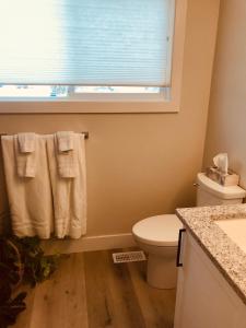 基洛纳Your home away from home的一间带卫生间的浴室和一个带毛巾的窗户。