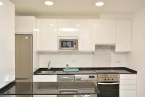 马德里4Torres Homes - Sofía的白色的厨房配有水槽和微波炉