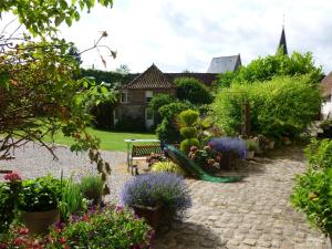 Marles-sur-Canche玛诺伊尔弗朗西斯住宿加早餐旅馆的鲜花盛开的花园,长凳和教堂