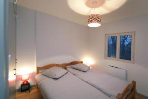 拉巴罗什Chalet les airelles的白色卧室设有2张床和2盏灯。