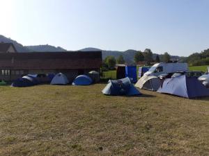 古察Dragacevska avlija - Camp的一组帐篷,位于建筑旁边的田野