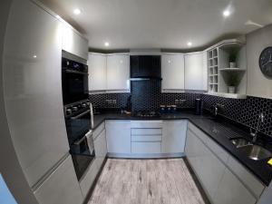 阿伯里斯特威斯46 Y Lanfa的厨房配有白色橱柜和炉灶烤箱。