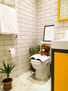 巴统Banana Apartments的泰迪熊坐在卫生间的浴室里