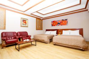 仁川市仁川机场女王酒店的一间卧室配有两张床、一张沙发和一把椅子