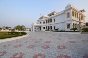 斋浦尔Umaid Farm Resort- A Legancy Vintage Stay In Jaipur的一座白色的大建筑,前面有一个庭院