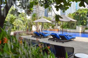 雅加达丽思卡尔顿酒店雅加达太古广场公寓的一组椅子和遮阳伞,位于游泳池旁