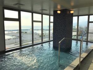 名户Green Rich Hotel Okinawa Nago (Artificial hot spring Futamata Yunohana)的一座大型游泳池,位于一座带窗户的建筑内