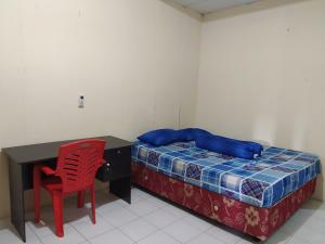 马卡萨OYO 3116 Batu Putih Homestay的一间卧室配有一张带书桌和红色椅子的床