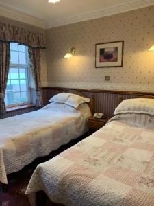 沃尔索尔林登之家宾馆的一间卧室设有两张床和窗户。