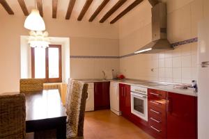 阿尔玛萨Casa rural Casa Fuerte San Gregorio I的厨房配有红色橱柜和桌椅