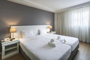 蓬塔德尔加达Hotel Gaivota Azores的酒店客房设有一张带两盏灯的大型白色床。