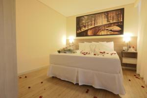 蒙蒂斯克拉鲁斯Hotel Amsterdam Montes Claros的卧室配有一张白色床,墙上挂有绘画作品