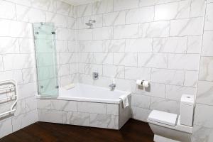 莱斯特城市客房酒店的白色的浴室设有浴缸和水槽。
