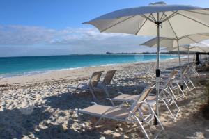 格雷斯湾The All New Grace Bay Suites的海滩上的一组椅子和一把遮阳伞