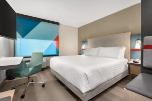 俄克拉何马城Avid Hotels - Oklahoma City - Quail Springs, an IHG Hotel的一间卧室配有一张床、一张桌子和一把椅子