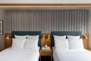 芝加哥21c Museum Hotel Chicago的配有白色枕头的酒店客房内的两张床