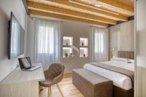 特雷维索Ca' dei Battuti Apartments的一间卧室配有一张床和一张带笔记本电脑的书桌