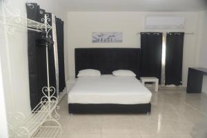 埃拉特红海酒店的一间卧室配有一张带白色床单和黑色窗帘的床。